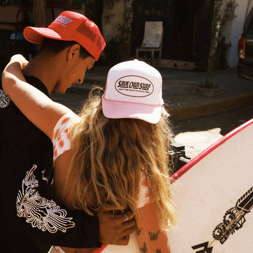 Two people embracing with a surfboard in an urban setting